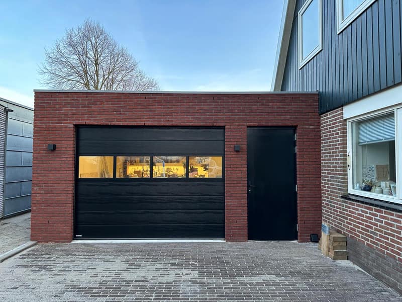 Nieuwgebouwde garage met zwarte sectionaaldeur
